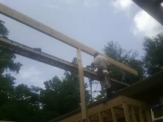 Carpenter setting a ridge beam over a new addition frame — Ice Dam Removal by Roofing Brothers in Harveysburg