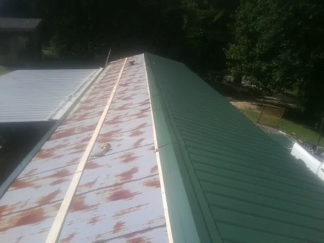 Old rusted panels beside newly installed green metal roofing — Wind Damage Roof Repair by Roofing Brothers in Harveysburg