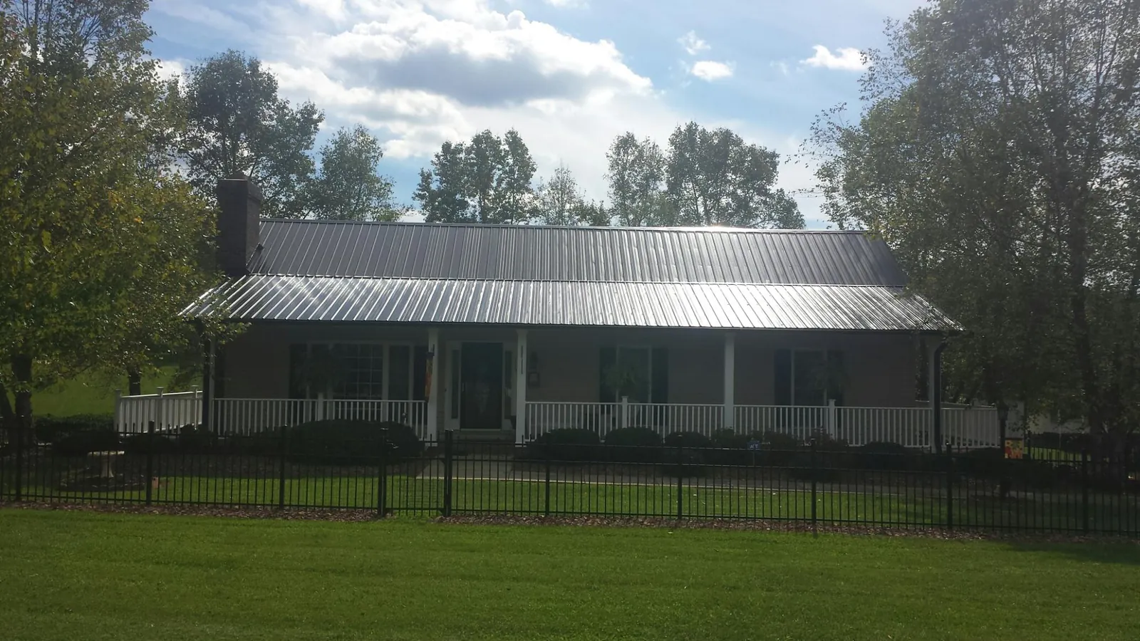 Gray metal roof on a brick ranch with a full width front porch — Gutter Guard Installation work by our crew in Harveysburg
