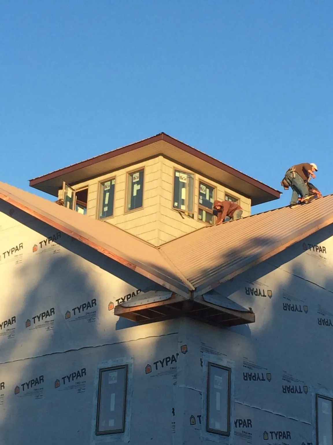 Roofers working around a rooftop cupola on a new metal roof at sunset — Roof Waterproofing in Harveysburg by Roofing Brothers